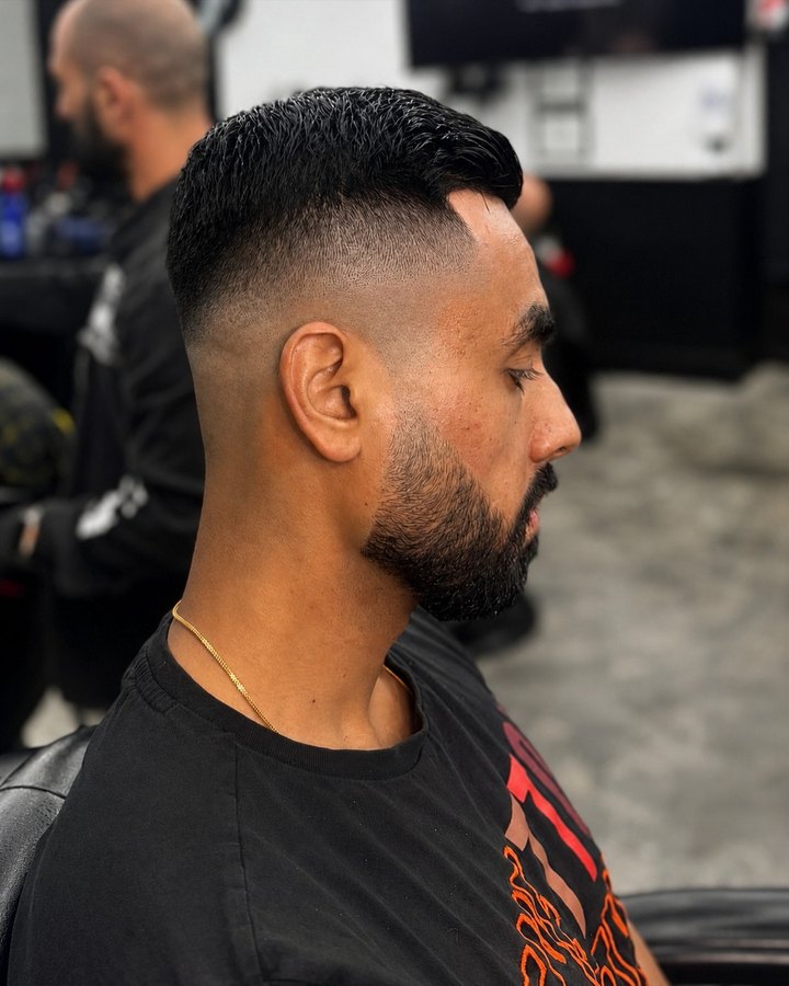 High skin fade with full beard, gold chain detail