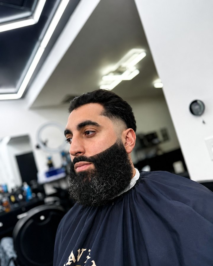 Tapered cut paired with a sculpted full beard, hex ceiling lights overhead