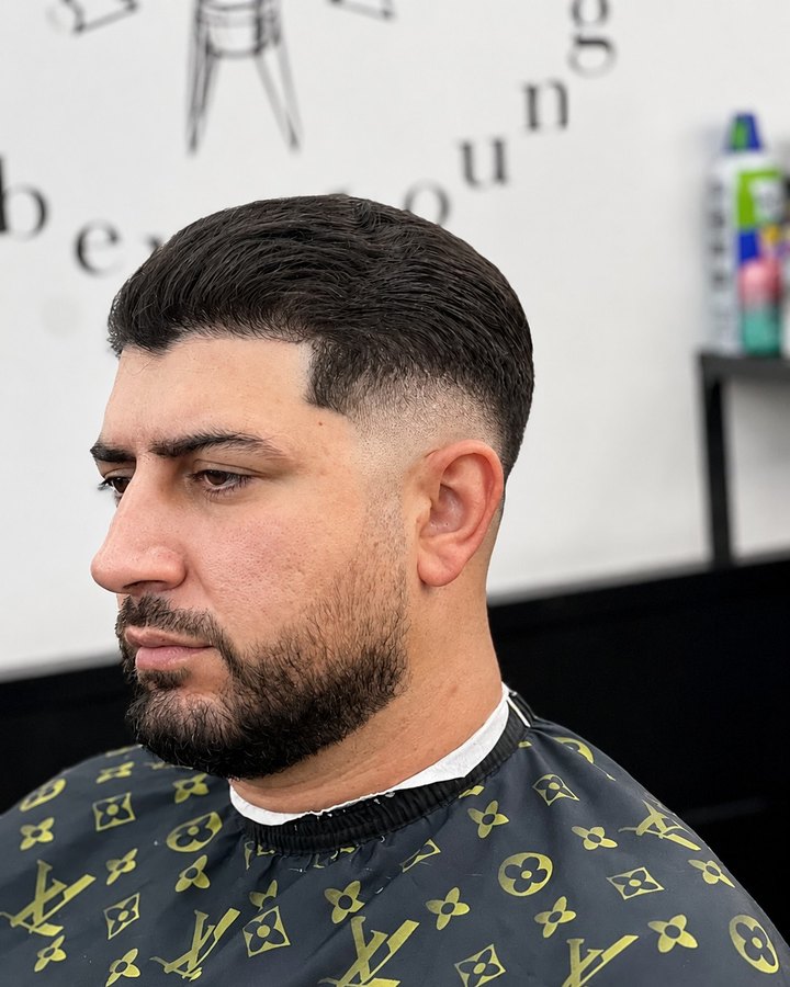 Side profile of a tapered cut and trimmed beard, Barber Lounge wordmark behind