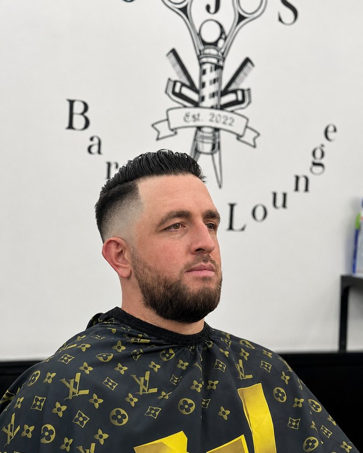 Pompadour fade with trimmed beard, framed by the Jojo's Barber Lounge wall mark
